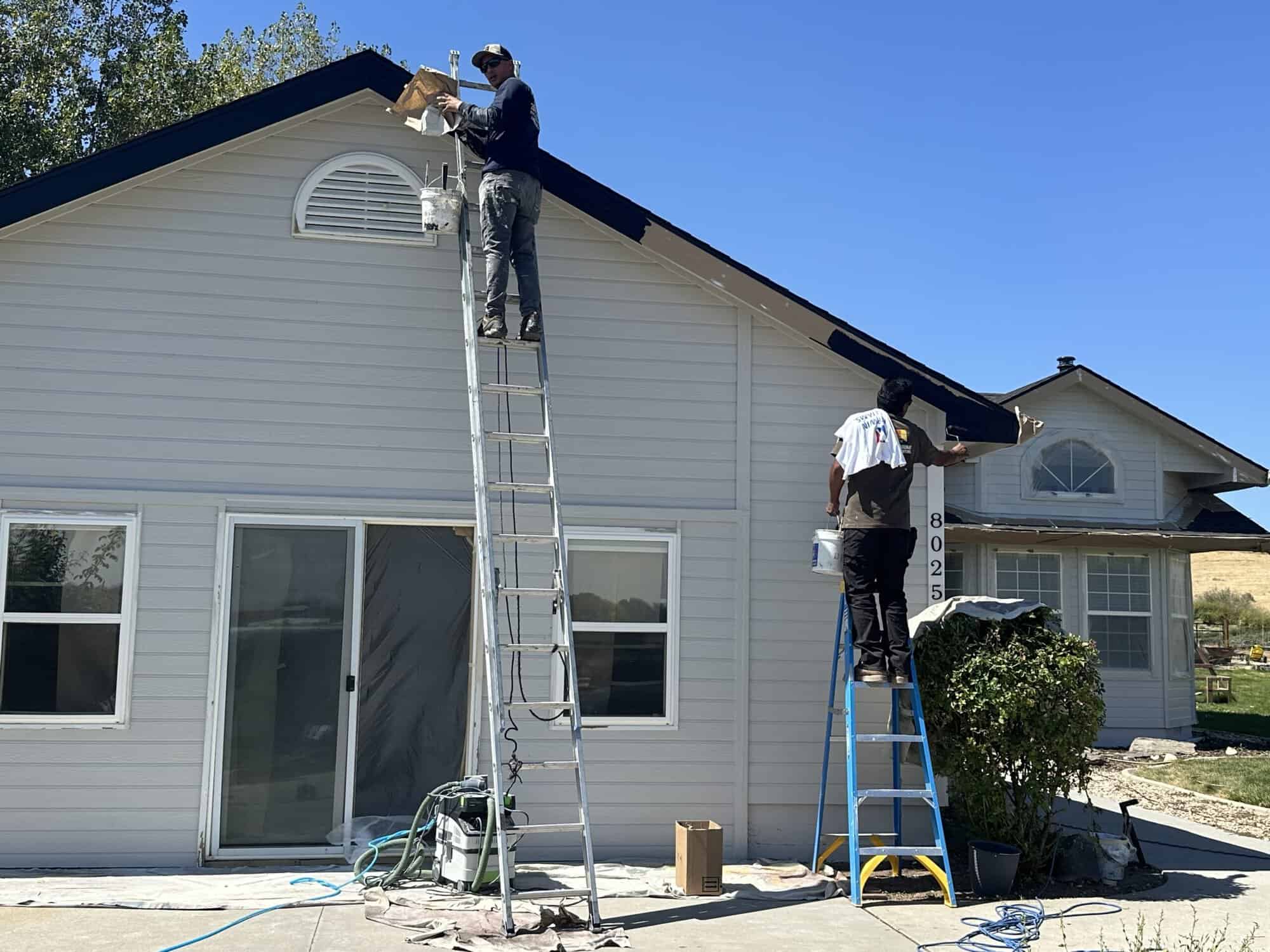 Two painters painting the roof.