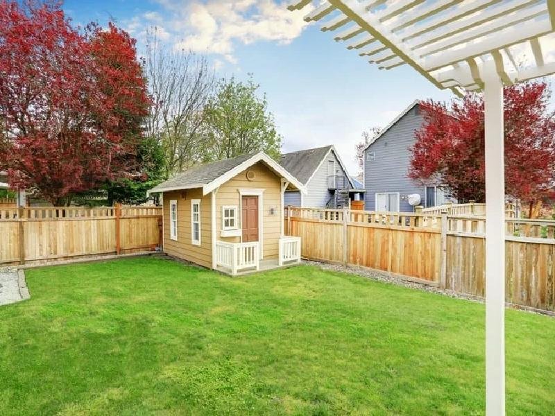 Tan backyard outbuilding with fresh paint and a wooden fence in a residential yard in the Treasure Valley, Idaho, painted by Lagunas Painting