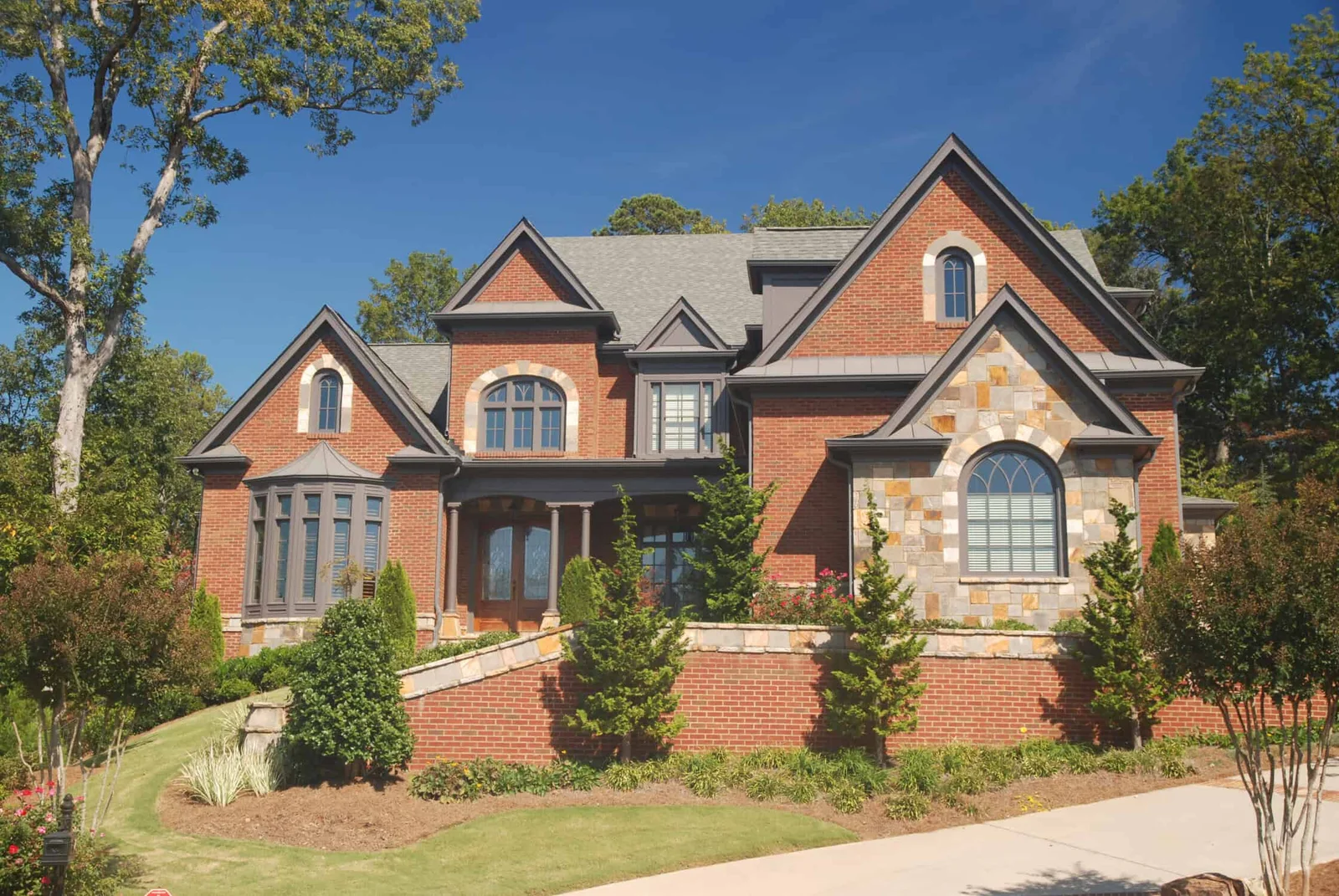 Large brick and stone house with arched windows and landscaped stone walkway, brick painting by Lagunas Painting in the Treasure Valley, Idaho