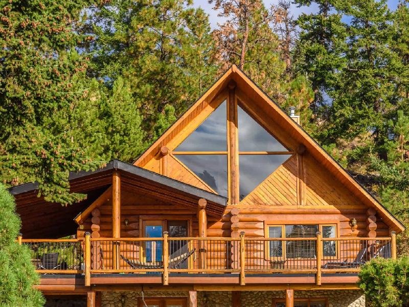 Log cabin with a rich golden wood stain surrounded by pine trees in Idaho, stained by Lagunas Painting