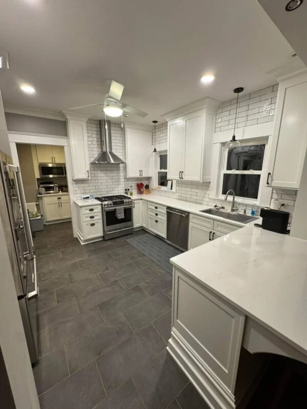 Freshly painted white kitchen cabinets with subway tile backsplash and dark tile flooring, cabinet painting by Lagunas Painting in Caldwell, Idaho