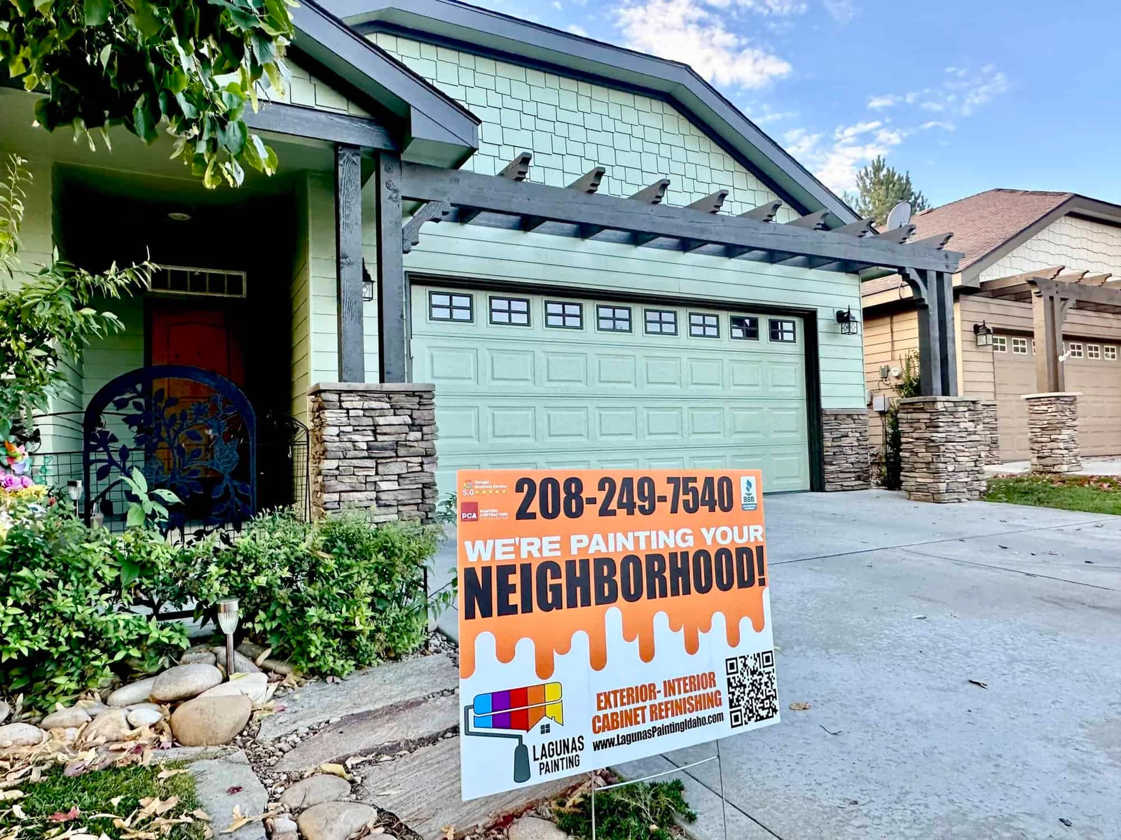 Freshly painted sage green two-story home with a stone accent garage entrance in Boise, Idaho, exterior house painting by Lagunas Painting