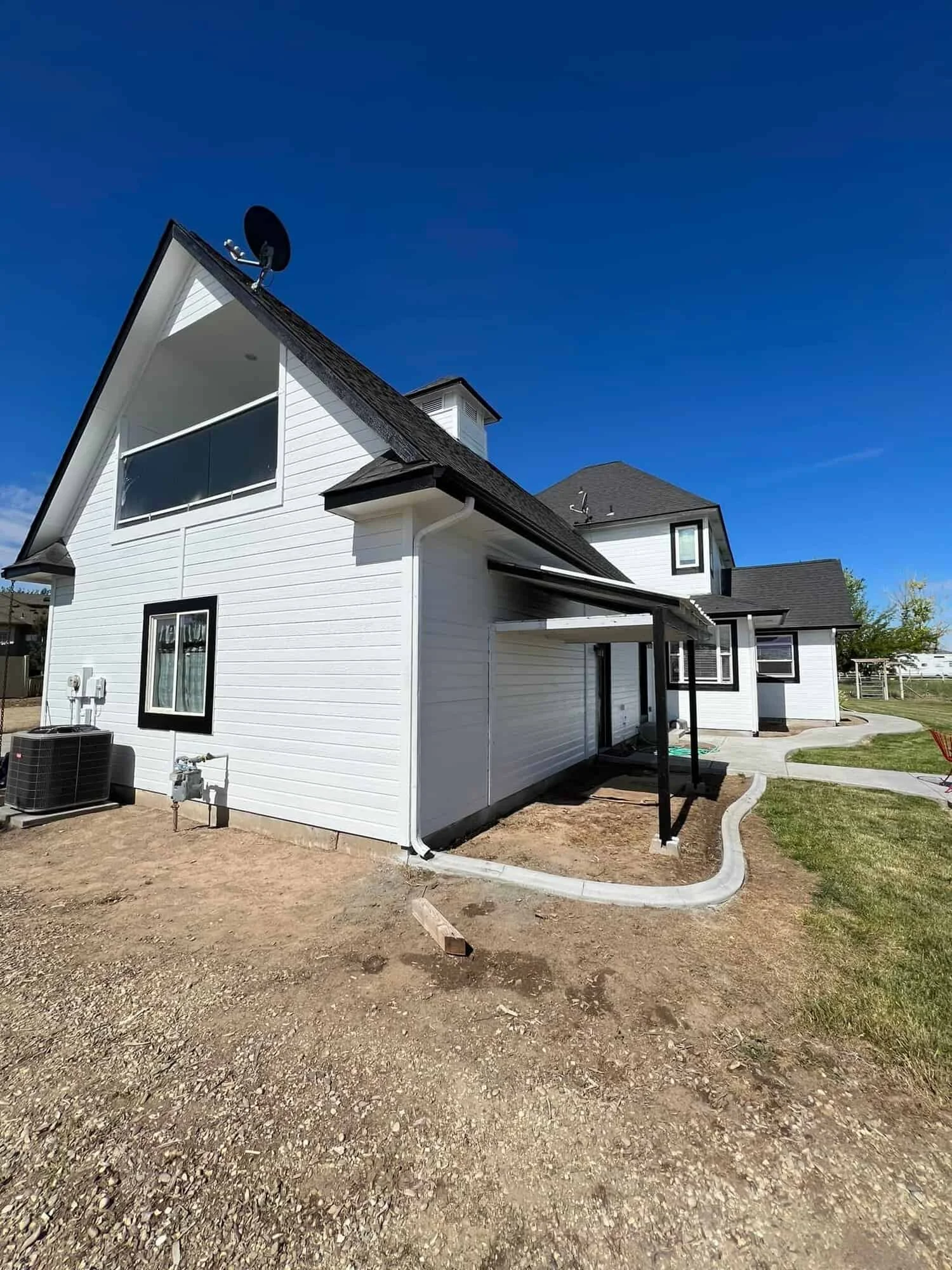 Freshly painted two-story white farmhouse-style home with black trim and a satellite dish, exterior house painting by Lagunas Painting in Eagle, Idaho