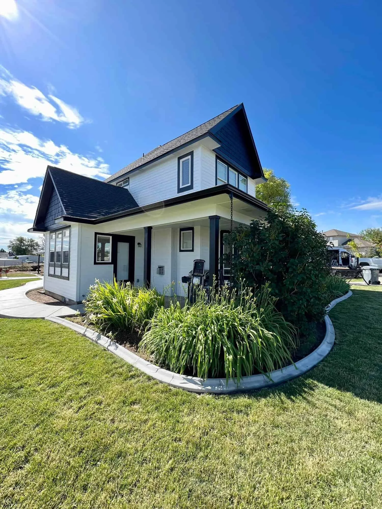 Freshly painted two-story white house with black trim and a dark shingle roof under a clear blue sky, exterior house painting by Lagunas Painting in the Treasure Valley, Idaho