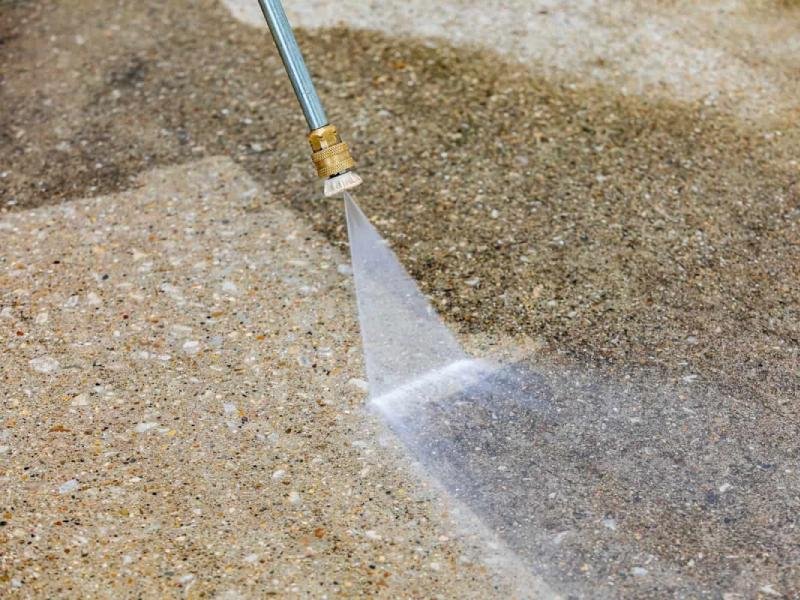 High-pressure water spray cleaning dirt from an exposed aggregate concrete surface at a home in the Treasure Valley, Idaho, by Lagunas Painting
