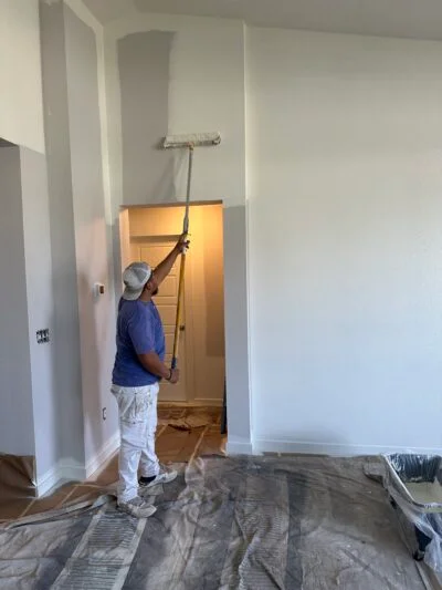Professional Lagunas Painting painter using a roller pole to paint high interior walls in Caldwell ID