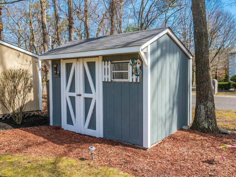 Gray backyard storage shed with white trim and barn-style doors, freshly painted by Lagunas Painting in the Treasure Valley, Idaho