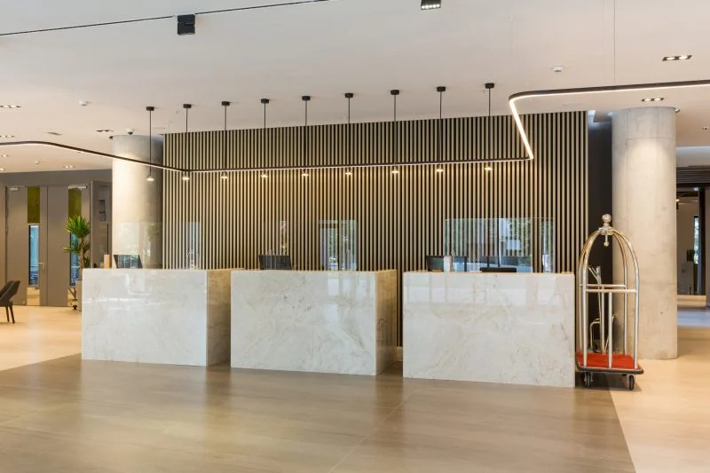 Sleek office reception area with a wood-slat accent wall and pendant lighting, interior commercial painting by Lagunas Painting